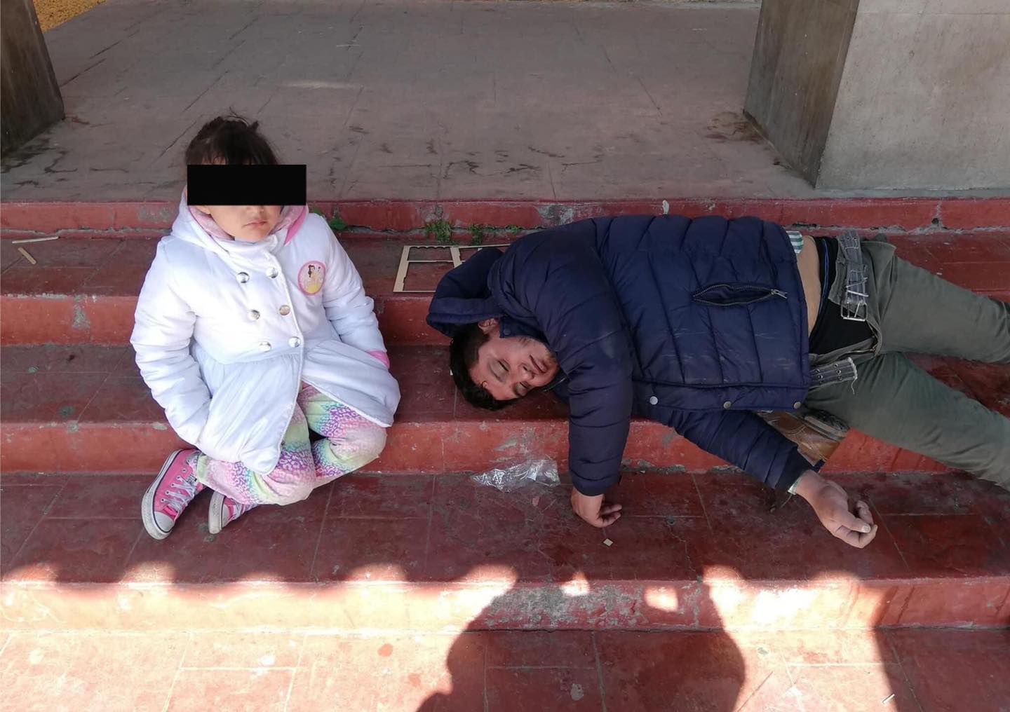 Niña acompaña a su papá mientras está tirado.