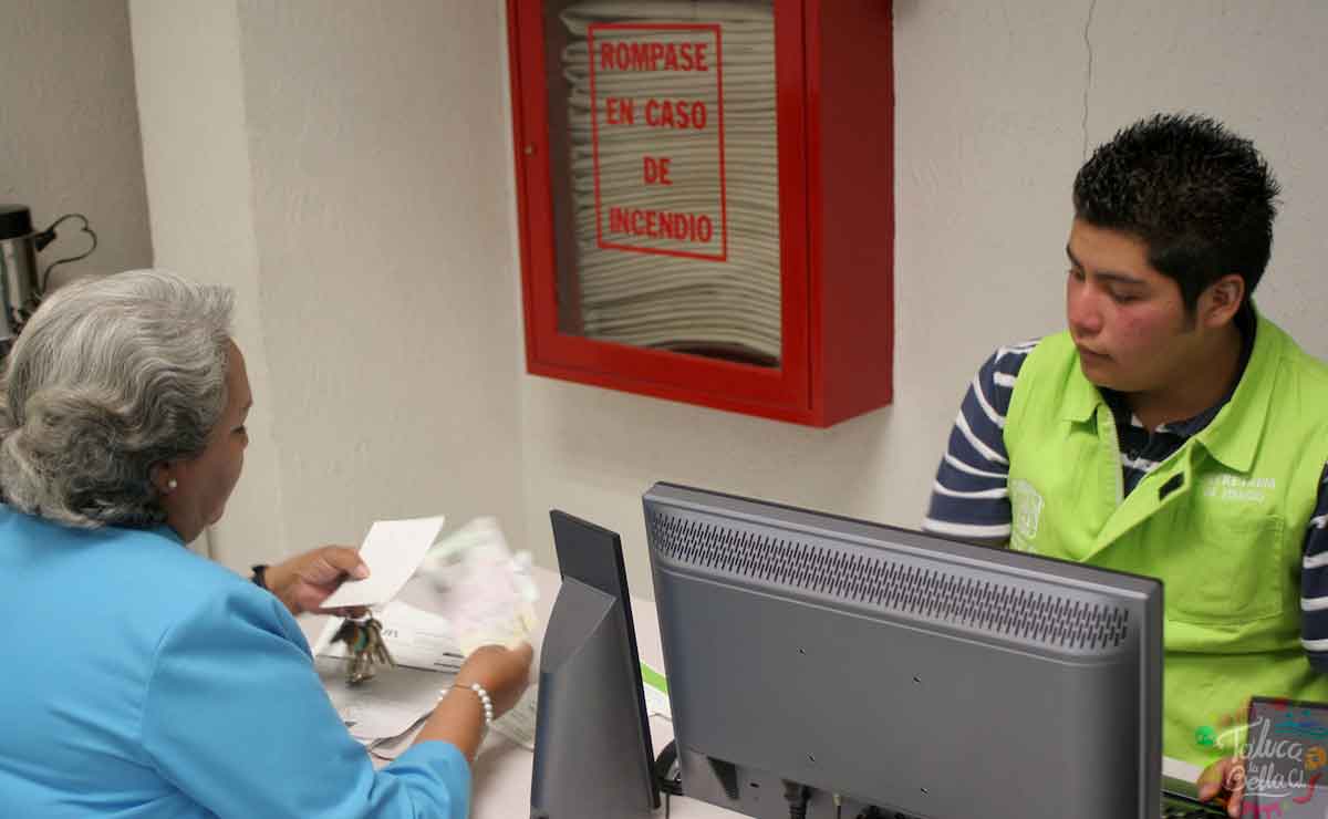Esta es la fecha límite de pago de tenencia 2021 en Edomex. Mujer realizando pago de placas.
