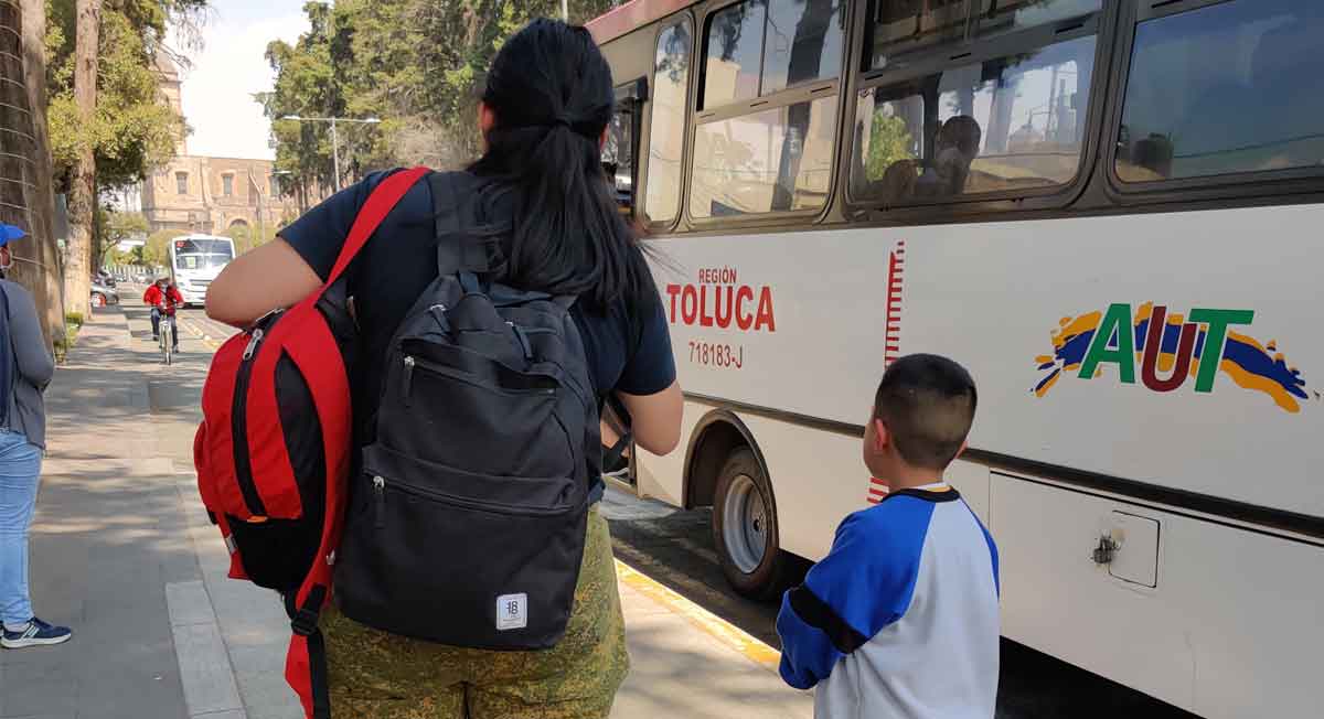 madre e hijo a la espera de abordar un autobus