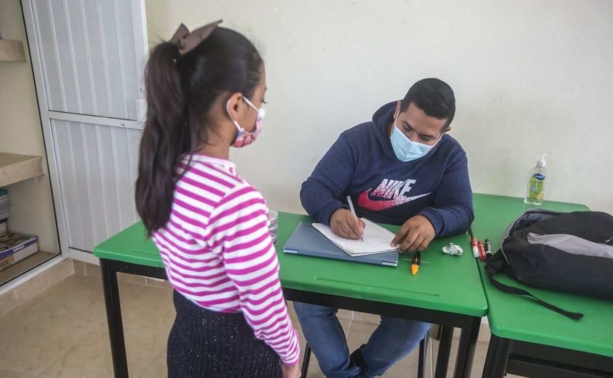 Alumnos y maestro en el salón de clases dando calificaciones, las cuales se podrán descargar a través del SIGED