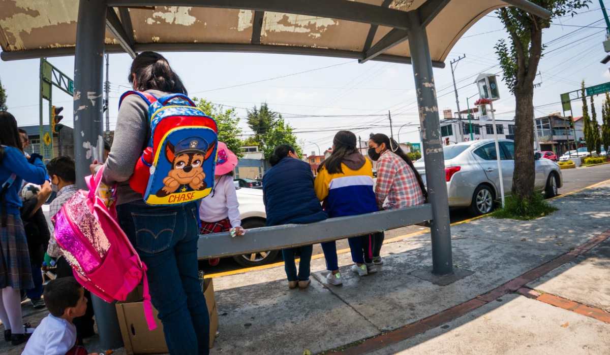 Padres de familia y alumnos esperando el camión a la salida de la escuela
