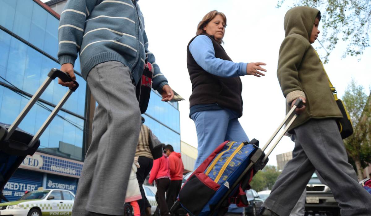 Papás e hijos cruzando la calle para entrar a la escuela