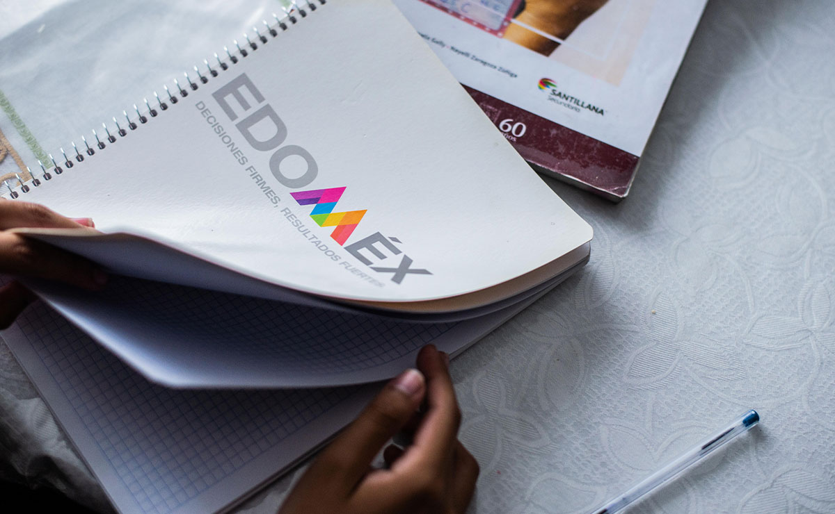 Mano escribiendo en libreta de los útiles escolares gratis en Edomex