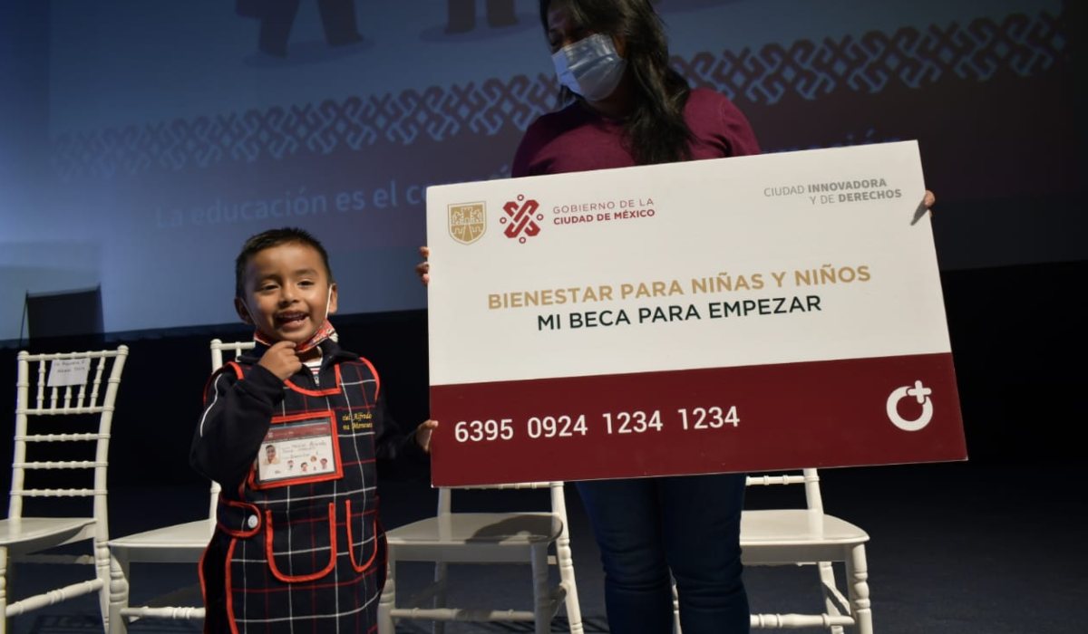 Alumno junto a una tarjeta gigante de Mi Beca Para Empezar 2022