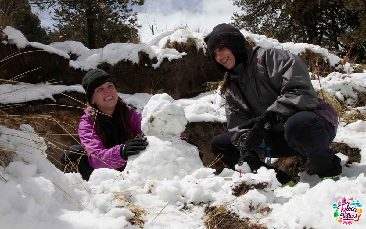 personas haciendo muñecos de nieve en nevado de toluca