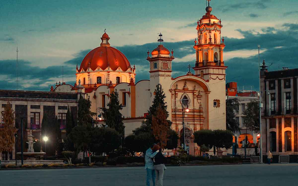 Pareja abrazados frente a una iglesia en el centro de Toluca en el ocaso del día